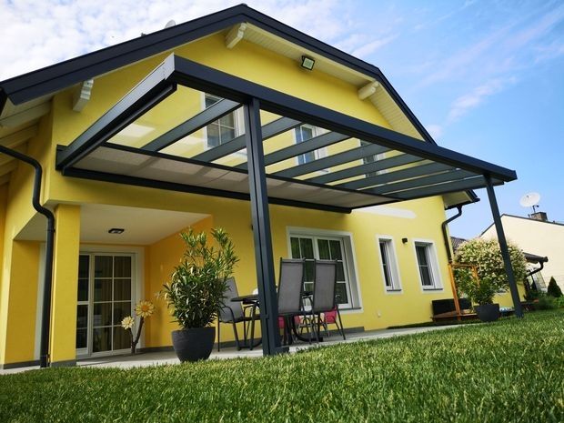 Ein Haus mit überdachtem Patio und einem Tisch auf der Terrasse.
