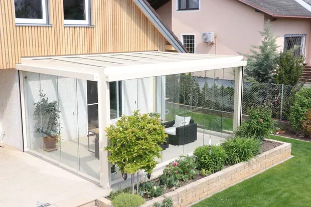 Ein verglaster Patio mit einem Tisch und Stühlen, ideal für entspannte Stunden im Freien.